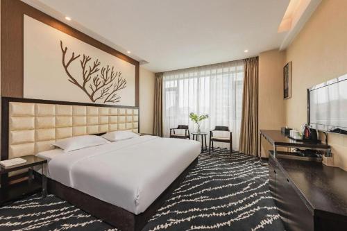 a hotel room with a large bed and a television at Kunming Long Way Hotel in Kunming