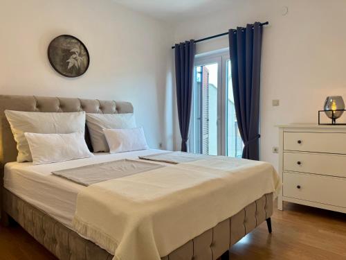 a bedroom with a large bed with blue curtains at Apartments Ein Haus in der Sonne in Malinska