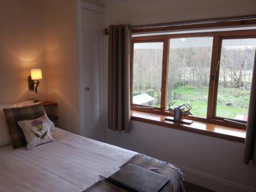 a bedroom with a bed with a large window at Ardlogie Guest House in Aviemore