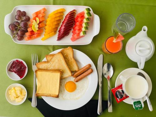 a table with a plate of breakfast food with eggs bread and fruit at Tropical Breeze Negombo in Negombo