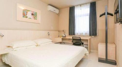 a bedroom with a bed and a desk and a window at Jinjiang Inn Changchun Xi An Avenue Branch in Changchun