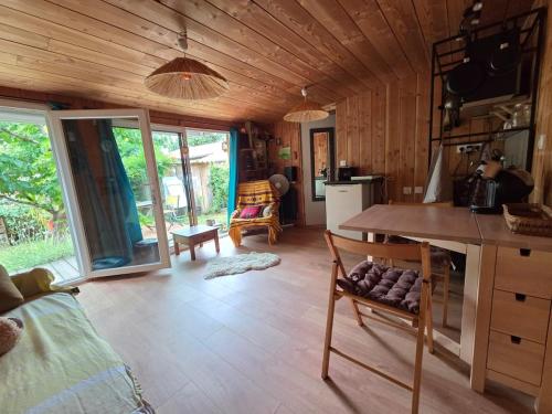 a kitchen with a table and chairs in a room at Studio bois avec terrasse et jardin bassin et océan in Le Teich