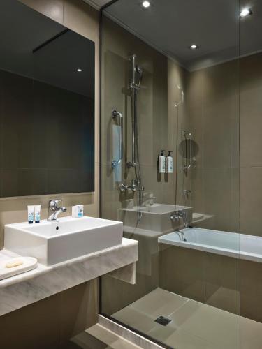 a bathroom with a sink and a shower and a tub at Aeolos Beach Resort in Gastouri