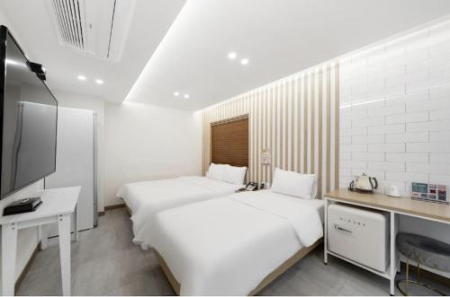 two beds in a room with a desk and a tv at Hotel Yaja Gwangju Mudeungsan branch in Gwangju