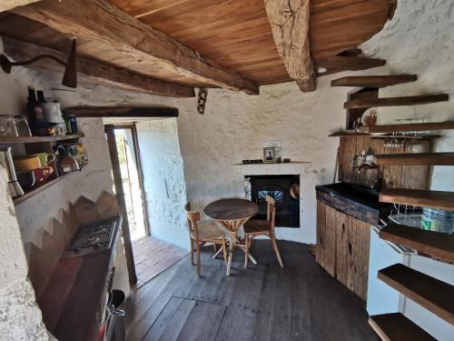 cocina con mesa, sillas y chimenea en Le Moulin de la Garenne, en Vibrac
