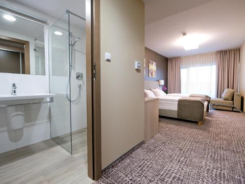 a hotel room with a bathroom and a bedroom at Hotel Molo Resort in Osiek