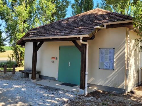 a small building with a green door and a sign at La Colline aux Fustes in Meurville