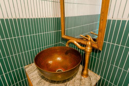 a copper sink in a green and white tiled bathroom at La Marrocco Villas in Nusa Penida