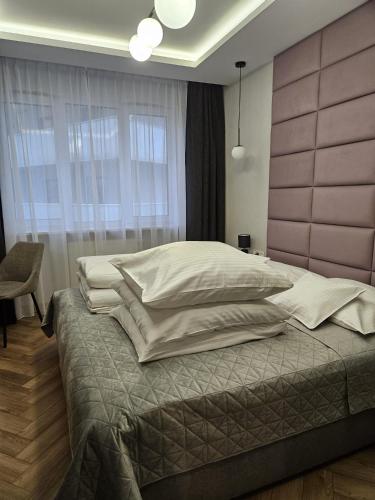 a bedroom with a large bed with white pillows at Central Park Green Apartament in Wrocław
