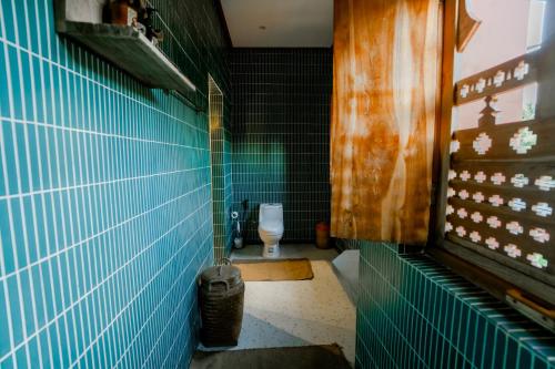 a bathroom with a toilet with blue tiled walls at La Marrocco Villas in Nusa Penida