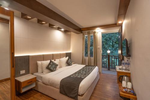 a bedroom with a large bed and a window at Excel Hotels & Resorts Mall Road Nainital in Nainital