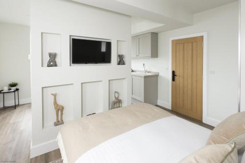 a white room with a bed and a flat screen tv at Bell House Oxford - The Dove in Oxford