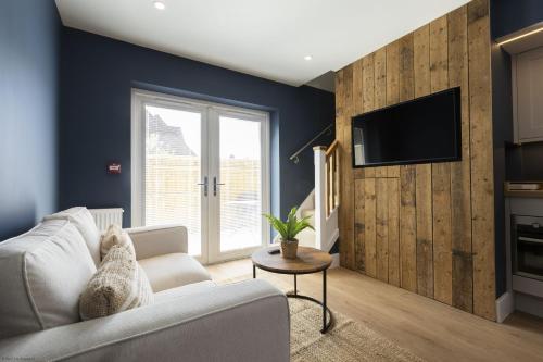 a living room with a white couch and a tv at Bell House Oxford - The Chalet in Oxford