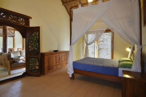 um quarto com uma cama de dossel e uma cadeira em Bruce's Hideout em Bumbang