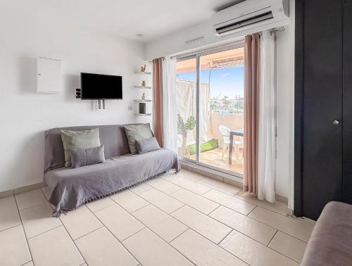 Una sala de estar con un sofá y una ventana grande. en Studio cosy 4 pers à 150m de la plage !, en Le Barcarès