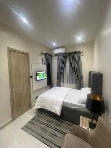 a bedroom with a bed and a television and a chair at Cozy 2BDR Apt In Lekki With Free WiFi & Swimming Pool in Ibeju