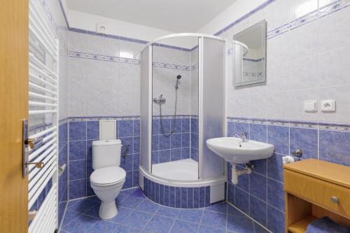 a blue tiled bathroom with a toilet and a sink at Vila Anna - Apartmány in Česká Lípa