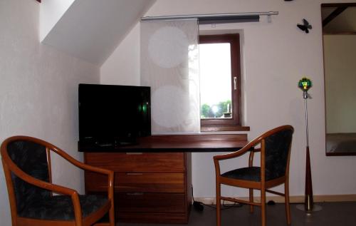 a room with a desk with a television and two chairs at Stone Station in Esneux