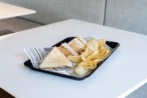 a plate of food with chips and sandwiches and a newspaper at ibis budget Madrid Aeropuerto in Madrid