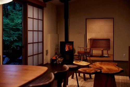 a living room with a stove and a table and chairs at SANU 2nd Home AMATSUMI 安曇野 in Azumino