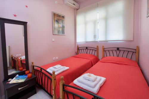 two beds in a bedroom with red sheets and a mirror at Sea Breeze Apartment in Sami