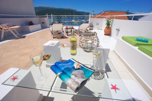 a glass table on a balcony with wine glasses at Sea Breeze Apartment in Sami