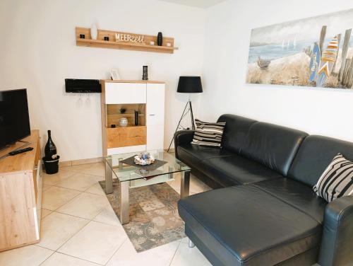 a living room with a black leather couch and a table at Residenz Strandkrone 02 in Kühlungsborn