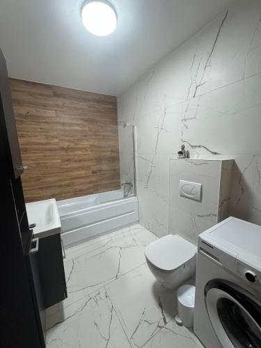 a white bathroom with a toilet and a bath tub at City Vibe Apartment in Baia Mare