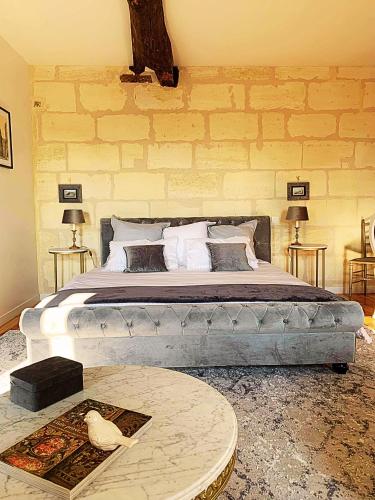 une chambre avec un grand lit avec un mur en pierre dans l'établissement Gîte Piscine SPA proche Bordeaux, à Lugon et l’Ile du Carney