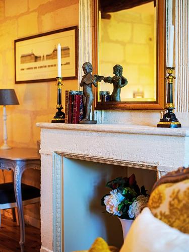 une cheminée avec une statue d'une fille prenant une photo dans un miroir dans l'établissement Gîte Piscine SPA proche Bordeaux, à Lugon et l’Ile du Carney
