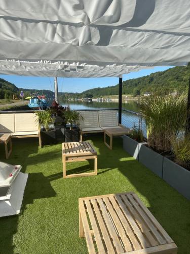 a patio with benches and a white canopy at Une perle ! Péniche complète pour 8 sur la Meuse, région Namur in Andenne