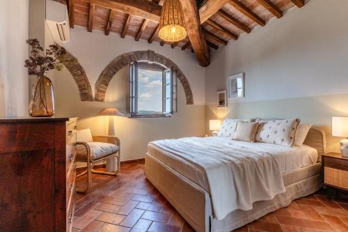 une chambre avec un lit, une chaise et une fenêtre dans l'établissement Nel cuore della Toscana con piscina, à Asciano