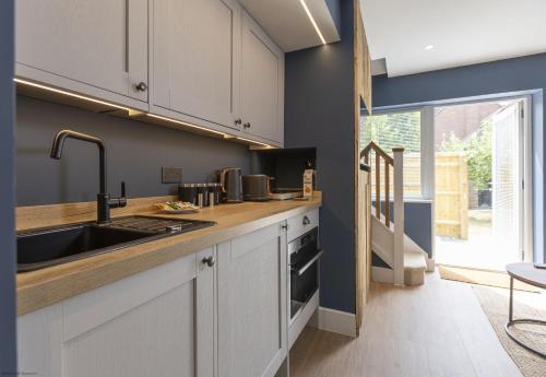 a kitchen with white cabinets and a sink at Bell House Oxford - The Noke in Oxford