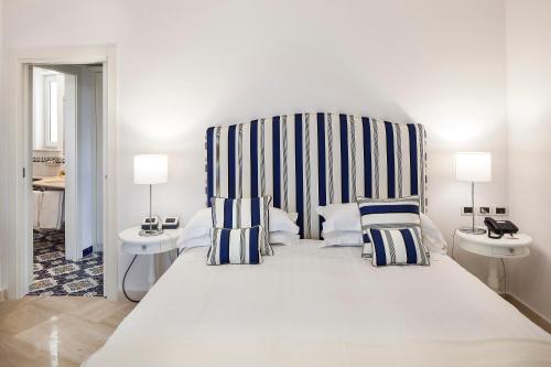 a bedroom with a large white bed with striped headboard at San Montano Resort & Spa in Ischia