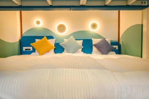 a bedroom with a large white bed with colorful pillows at KAMENOI HOTEL Atami in Atami