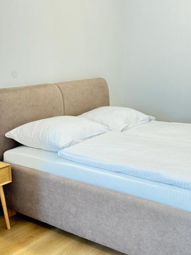a bed with white sheets and pillows on it at Riverside Apartment Praha in Prague
