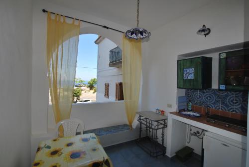 a kitchen with a window with a table and a chair at Vulcanoconsult Appartamenti Spiaggia in Lipari