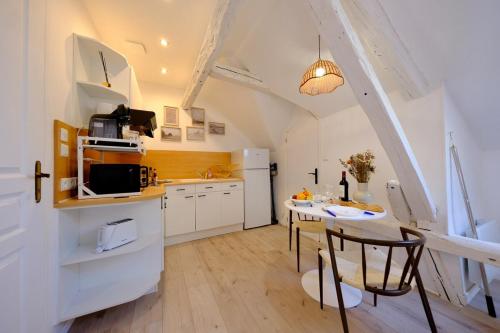 a kitchen with a table and a kitchen with white cabinets at Verneuil sur Avre - Romantic room in Verneuil d’Avre et d’Iton