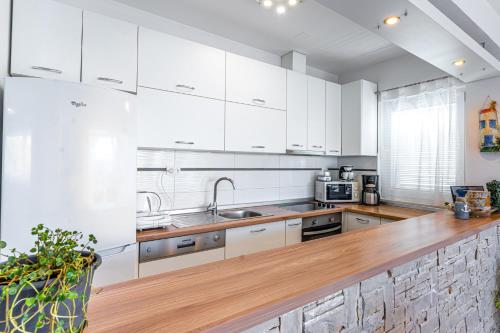 a kitchen with white cabinets and a wooden counter top at Apartments Nina in Maslenica