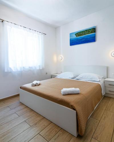 a white bedroom with a bed with two towels on it at Apartments Nina in Maslenica