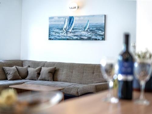 a living room with a couch and a table with a bottle of wine at Apartments Nina in Maslenica