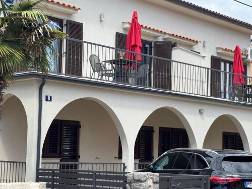 a house with a balcony with red umbrellas at Apartments Ein Haus in der Sonne in Malinska