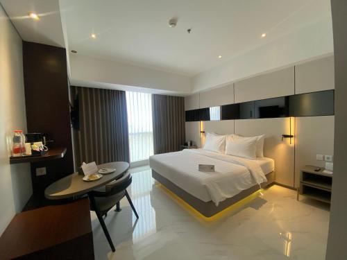 a hotel room with a bed and a table and a desk at Grand Whiz Hotel Praxis Surabaya in Surabaya