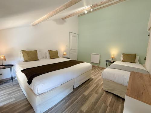 deux lits dans une chambre aux murs blancs et au parquet dans l'établissement Les gîtes du pied mulet, à La-Gripperie-Saint-Symphorien