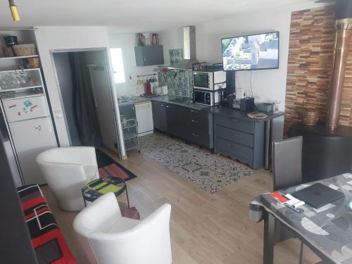 - une cuisine avec des chaises blanches et un comptoir dans l'établissement Chalet rustique à La Salvetat-sur-Agout avec vue montagne, à La Salvetat-sur-Agout