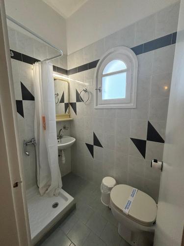a white bathroom with a toilet and a sink at Syros Rooms & Apartments in Posidhonía