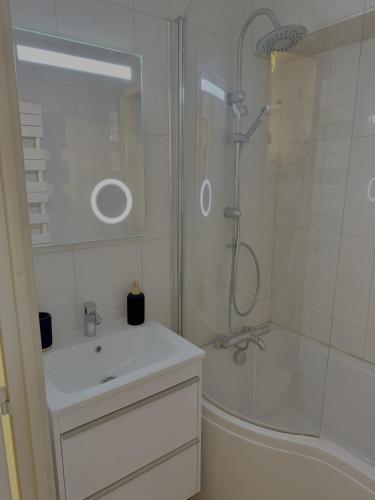 Un baño blanco con ducha y lavabo. en Les Duc(s) de l'Airelle, en Les Carroz d'Araches