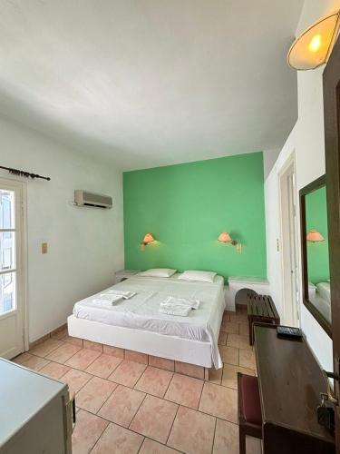 a bedroom with a bed and a green wall at Syros Rooms & Apartments in Posidhonía