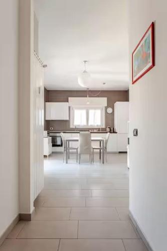 a white kitchen with a table and a dining room at Forum-San Siro Moderno Attico con WIFI e AC in Corsico