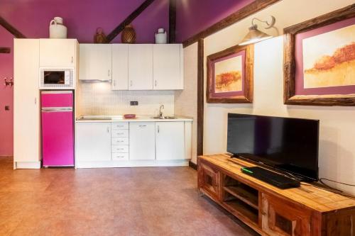 a kitchen with white cabinets and a tv on a table at Apartamentos Rurales & Spa La Bárcena in Enterria